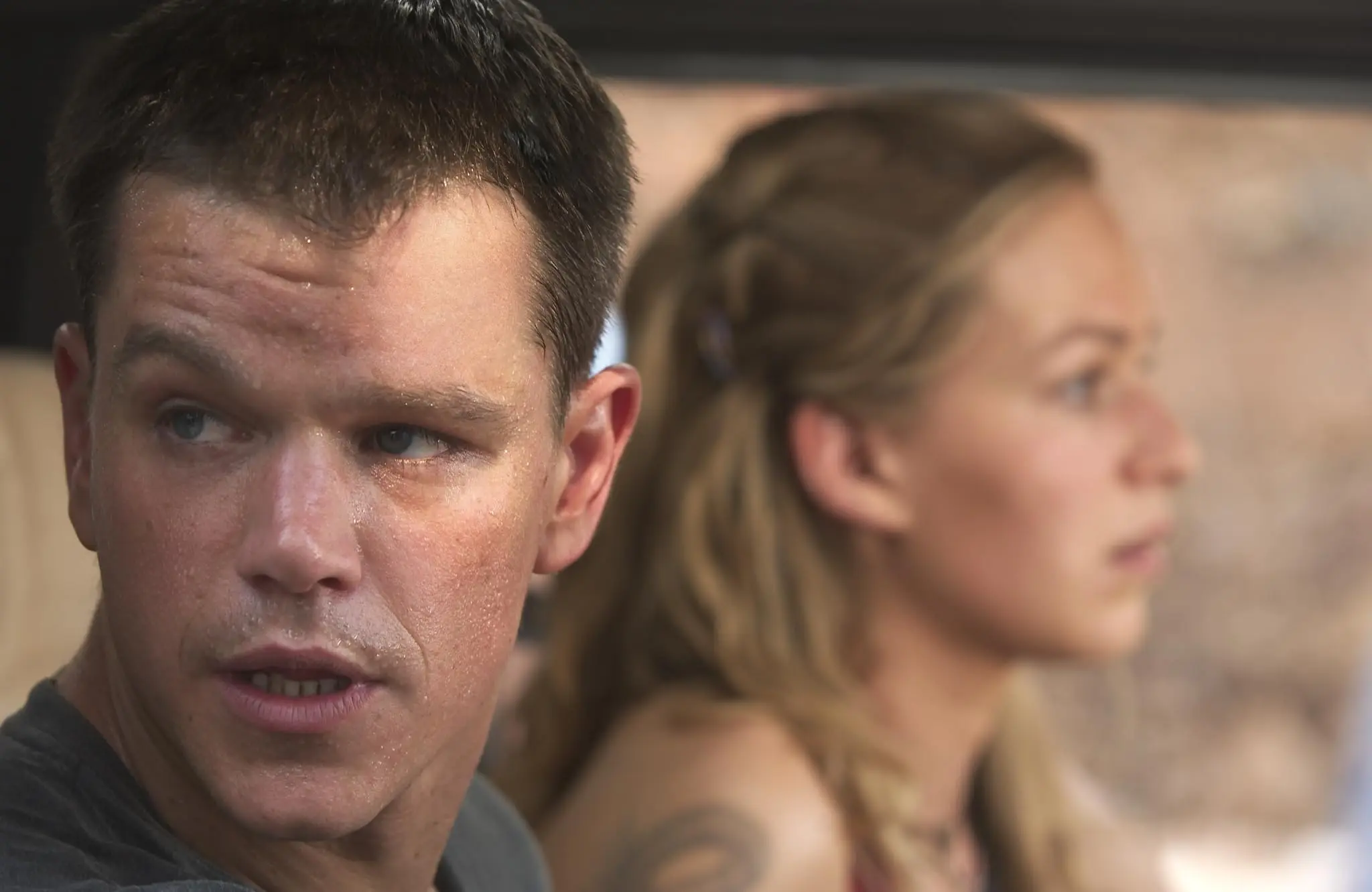 Jason Bourne (Matt Damon) gazes at an assassin while Marie (Franka Potente) drives.