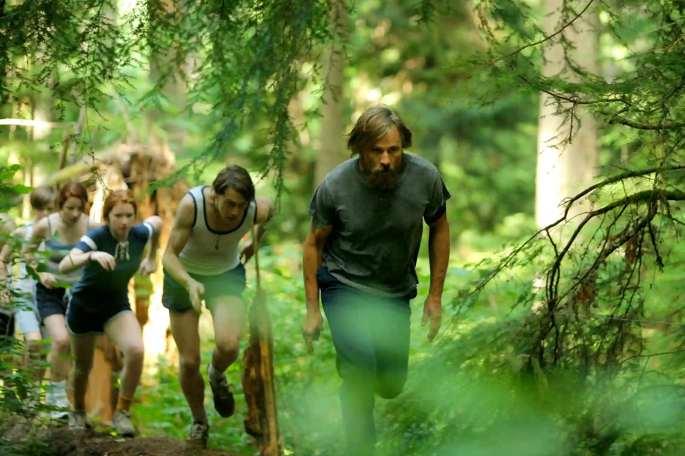 A family, living in a state park, runs through the woods.