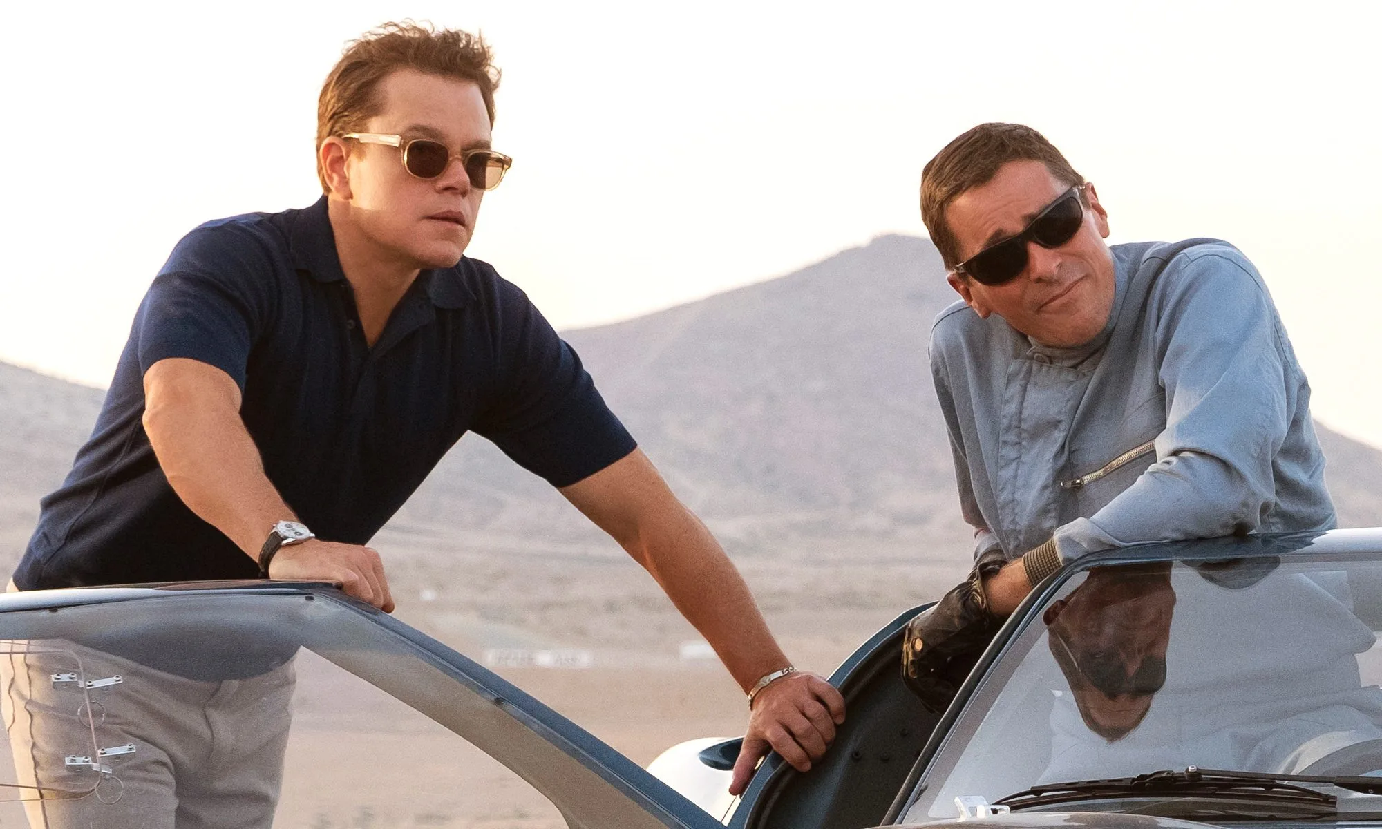 Richard Shelby (Matt Damon) and Ken Miles (Christian Bale) look up from a car.