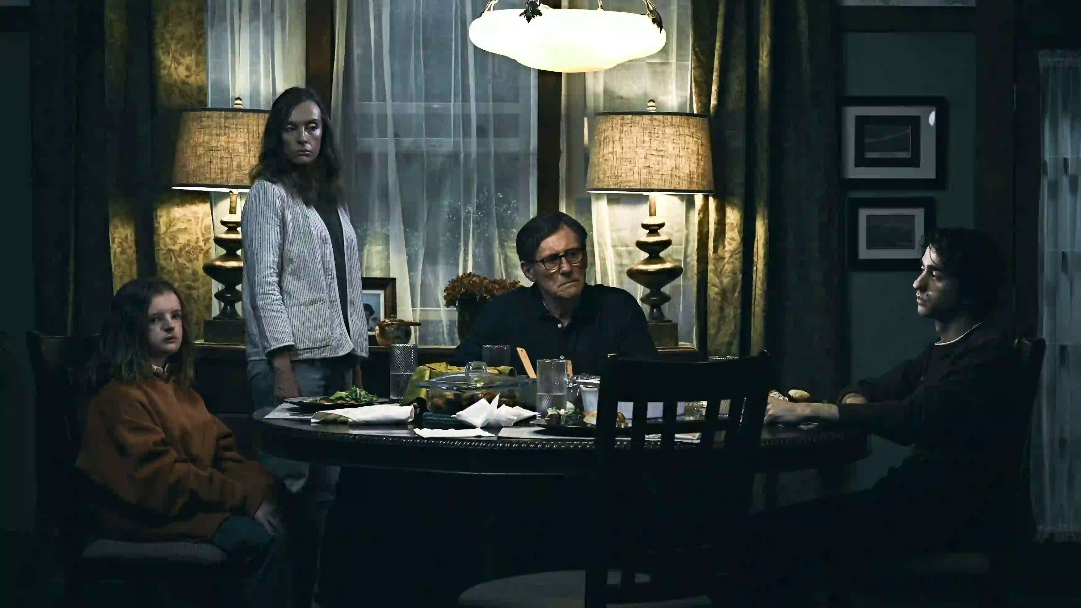 A disturbed family sits around a dinner table.