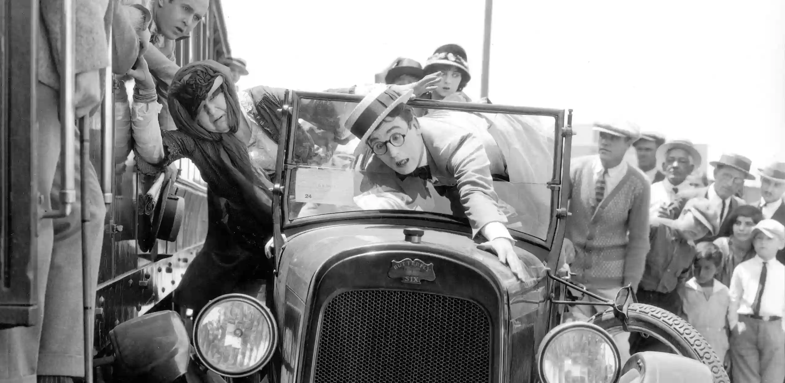 Harold Lloyd, a film star of the Silent Era, slides down the hood of a car as it crashes into a train.