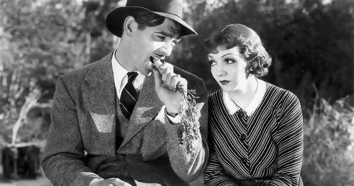 Clark Gable and Claudette Colbert wait by the roadside as hitchhikers.