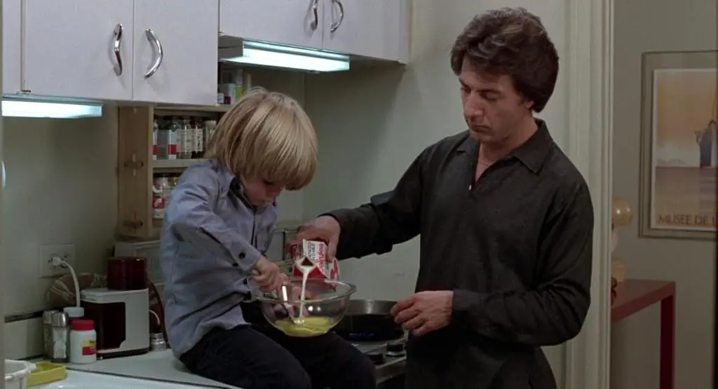 Ted (Dustin Hoffman) pours milk into eggs with his son, Billy (Justin Henry).