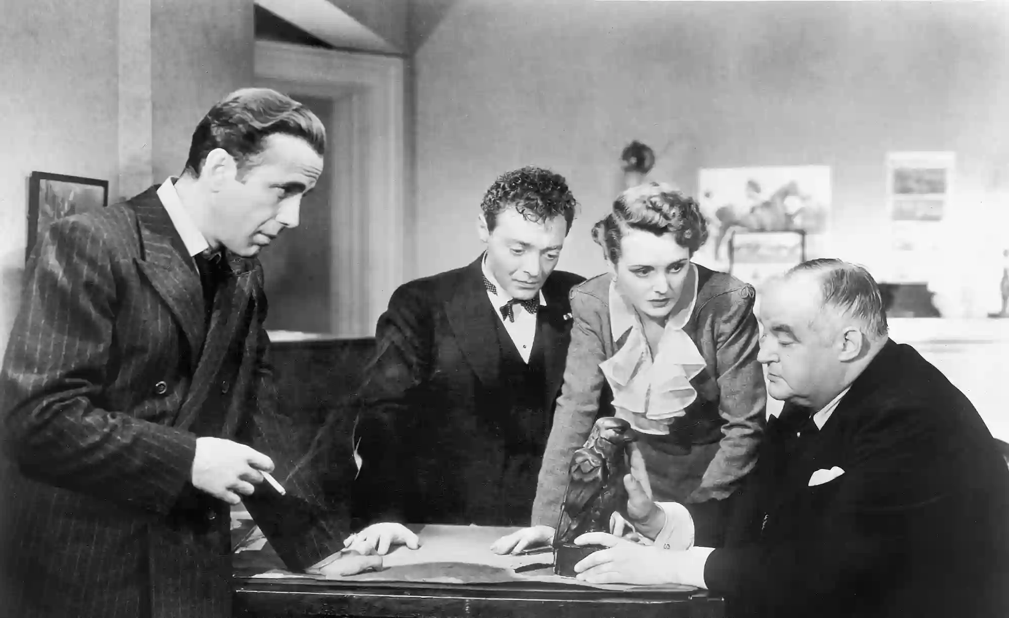 The four main characters gather to discuss a trophy: the Maltese Falcon.