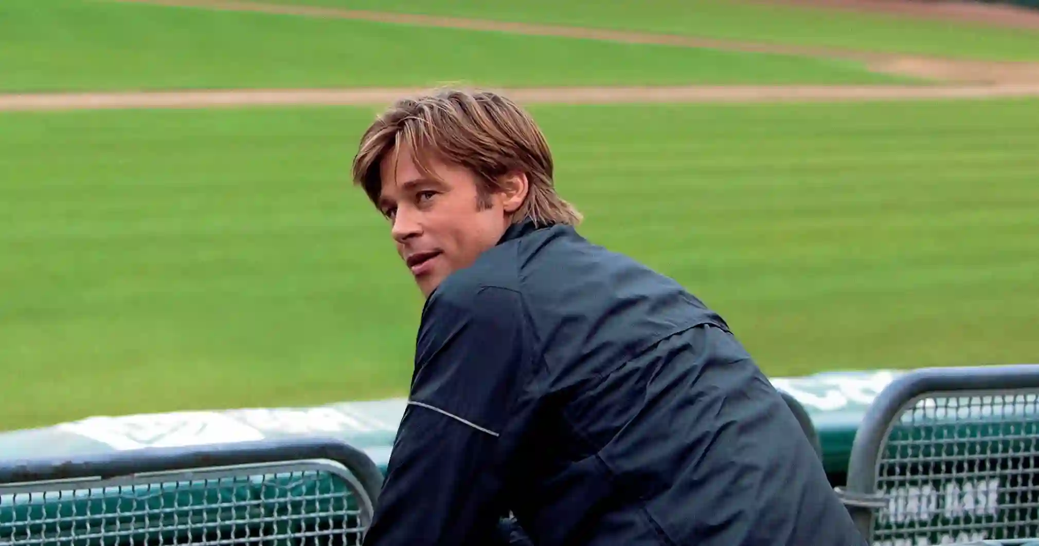 Link to Moneyball movie review Brad Pitt sits in a baseball stadium.