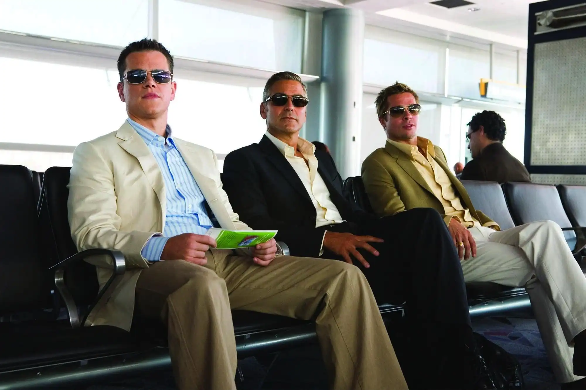 Clooney, Pitt, and Damon sit together at an airport.