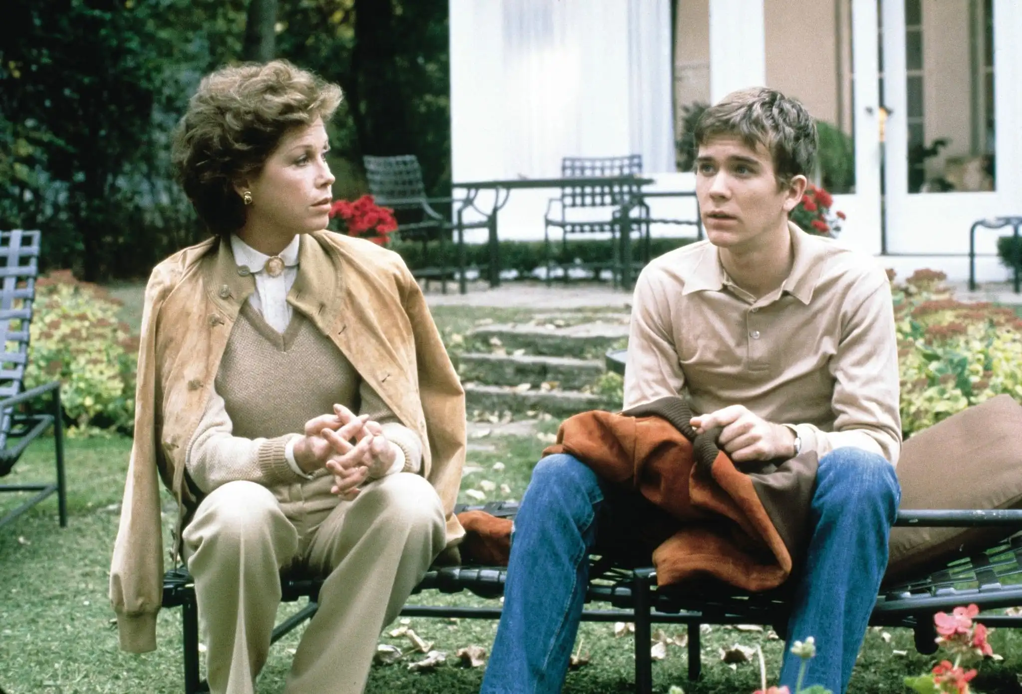 A mother and son discuss something outside in their backyard.