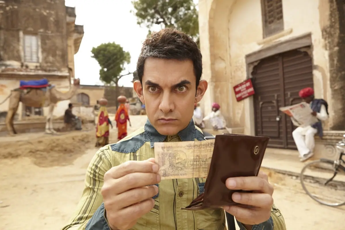 An alien holds an Indian rupee in his hands and wonders.