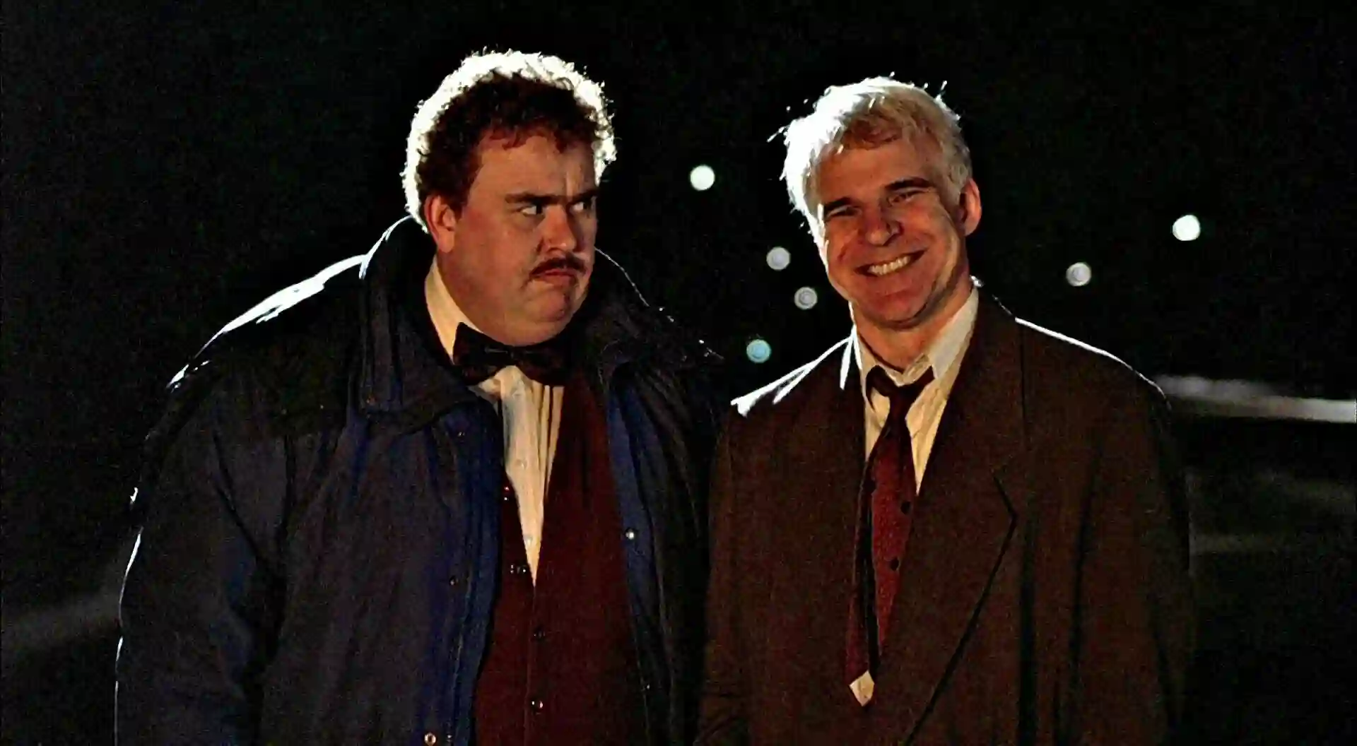 Steve Martin and John Candy sit together.