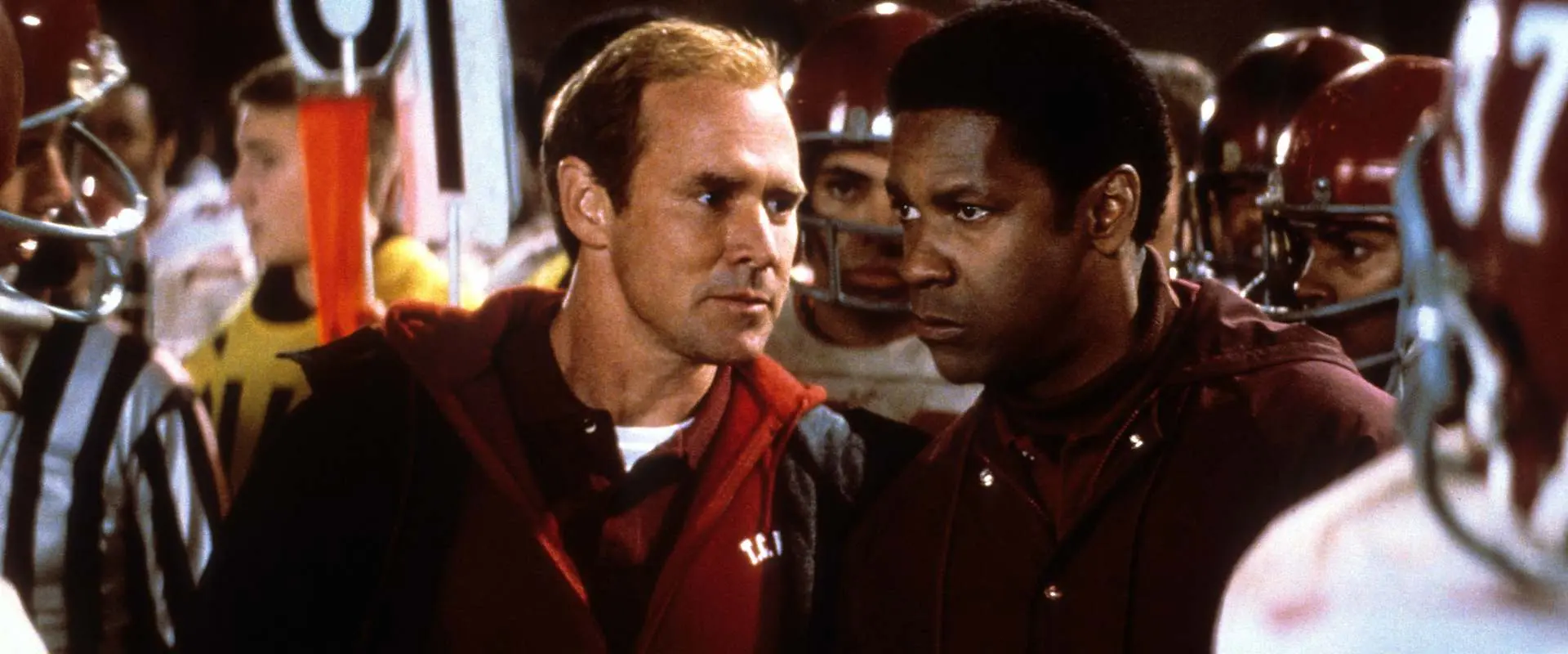 Two football coaches discuss their game strategy on the sidelines.