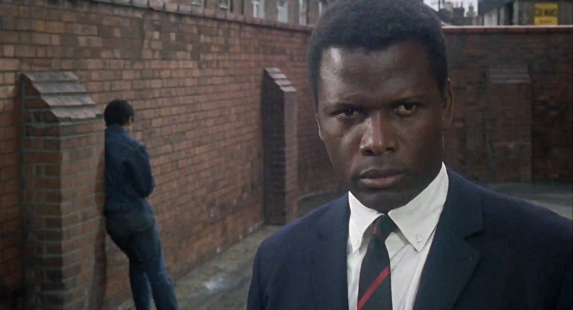 Sidney Poitier looks at the audience, worried about a disaffected youth behind him.