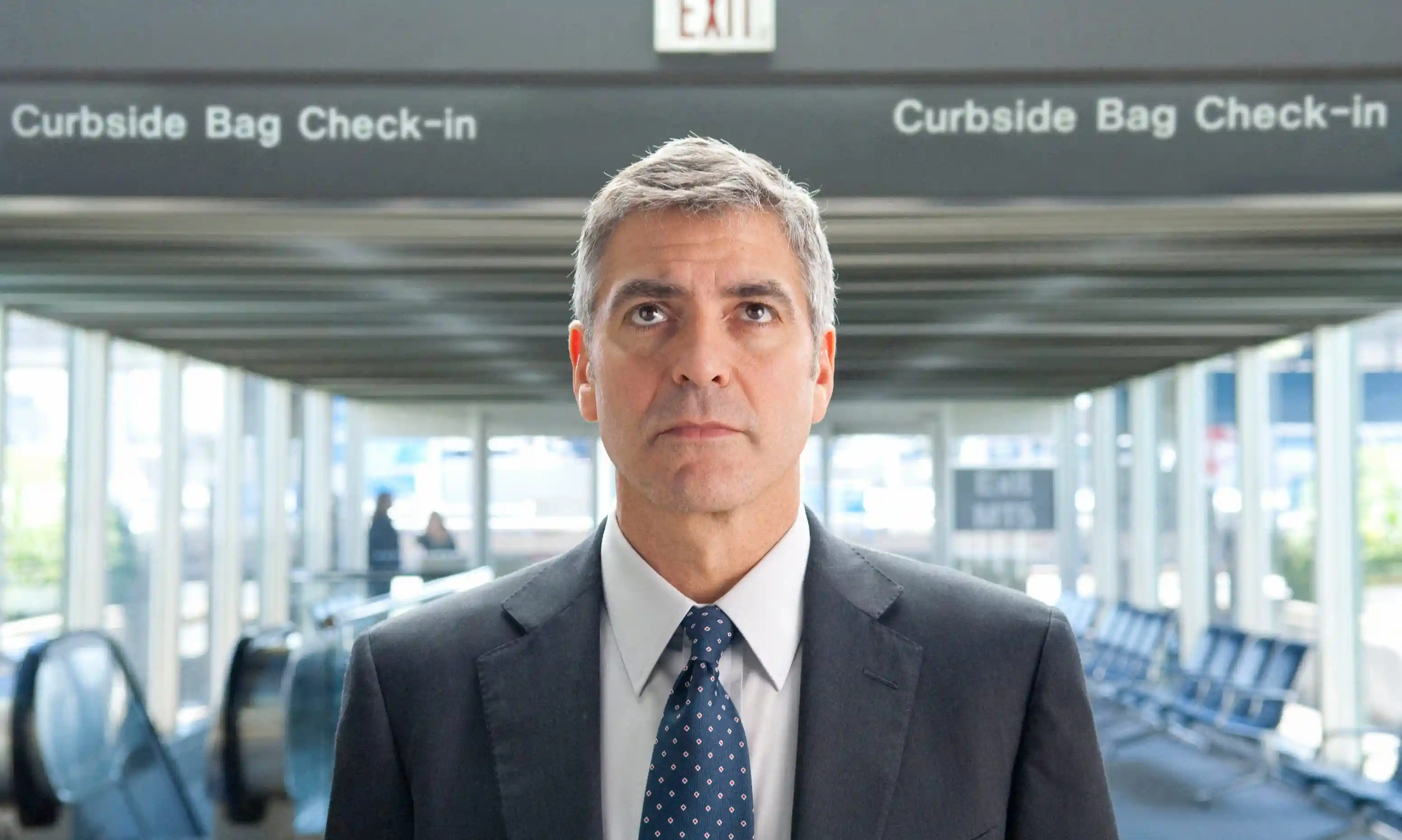 Ryan Bingham (George Clooney) looks at the flight board.