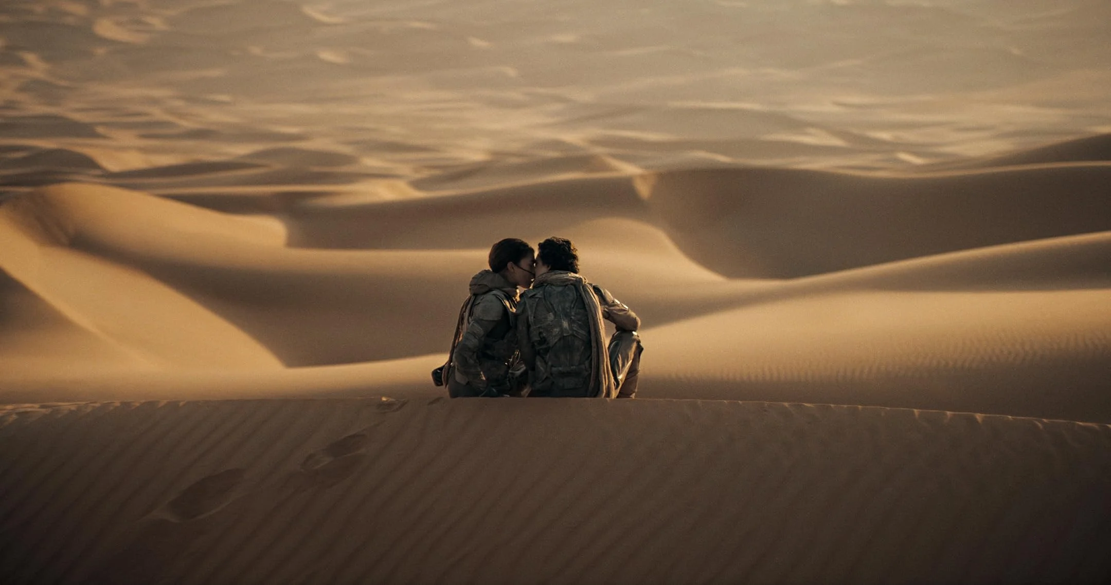 Paul Atreides (Timothée Chalamet) and Chani (Zendaya) kiss in the desert.