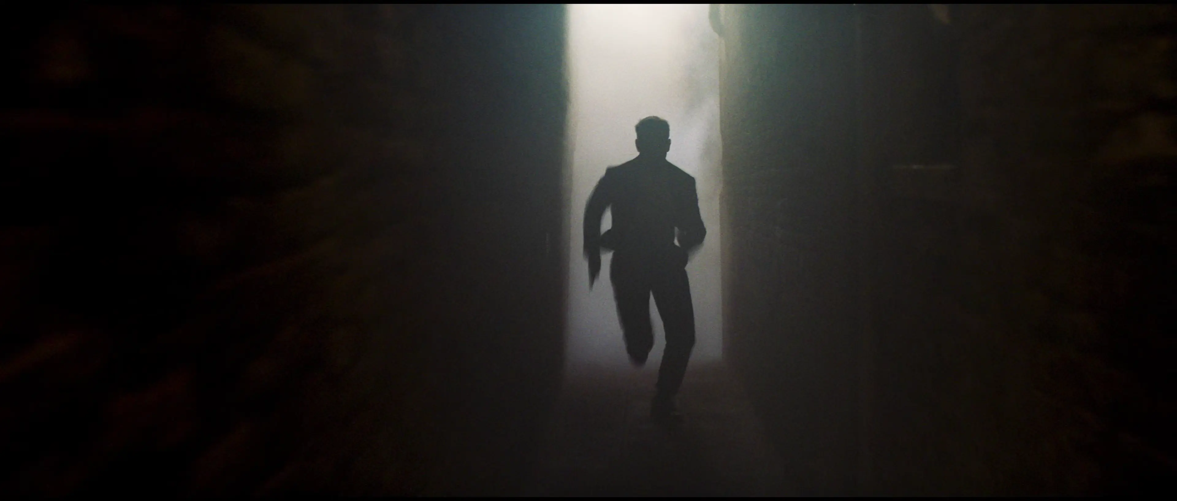 Tom Cruise runs through steam in an alley in Venice.